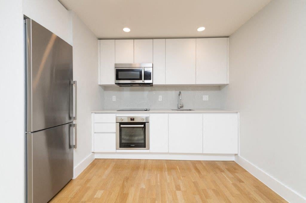 a kitchen with white cabinets and a stainless steel refrigerator